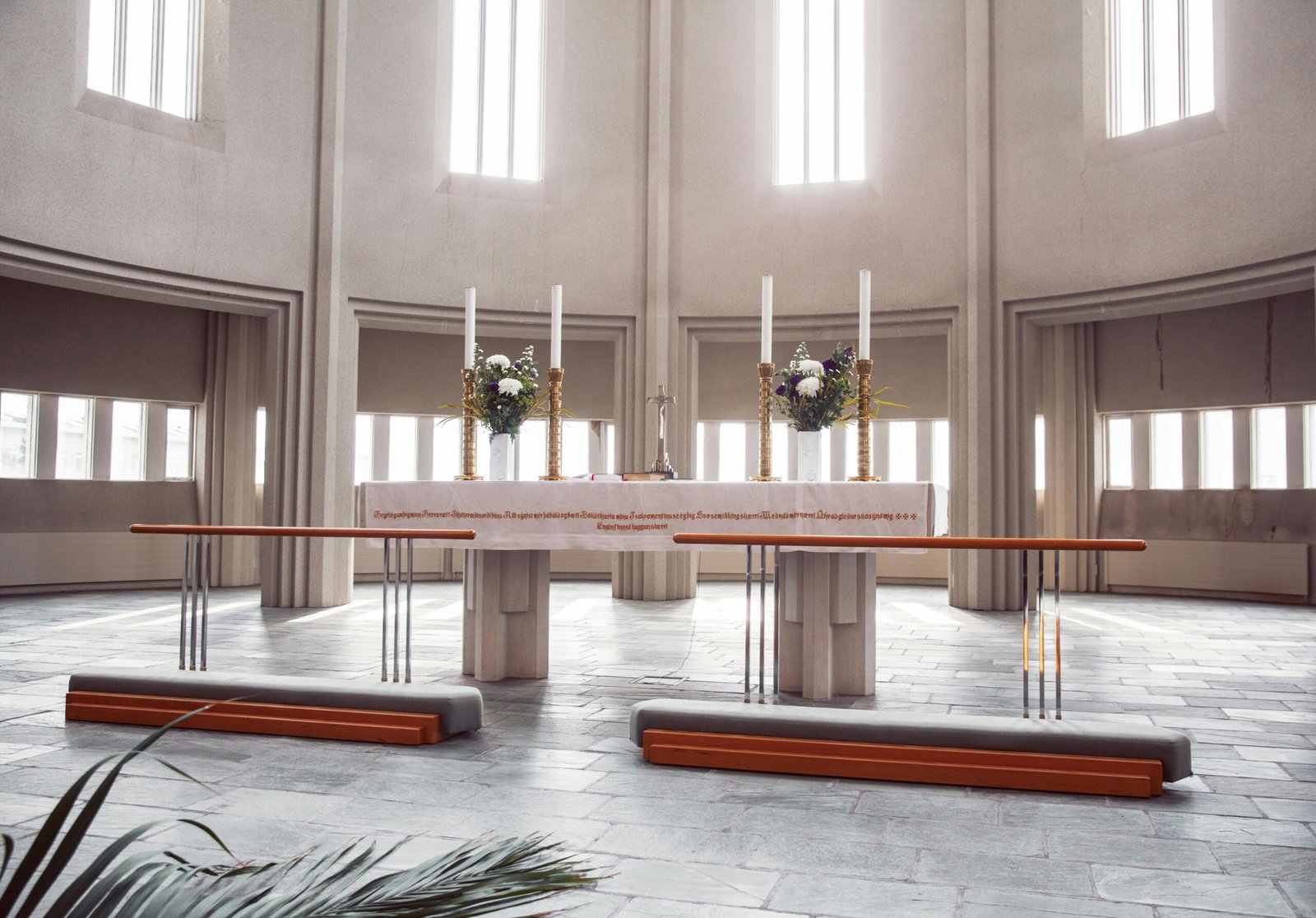 A spacious modern church altar with candles, flowers, and natural light.